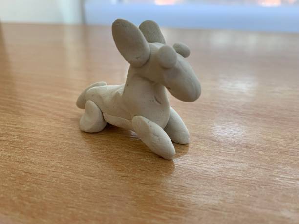 Small clay made white dog on a wooden table with a blurry background