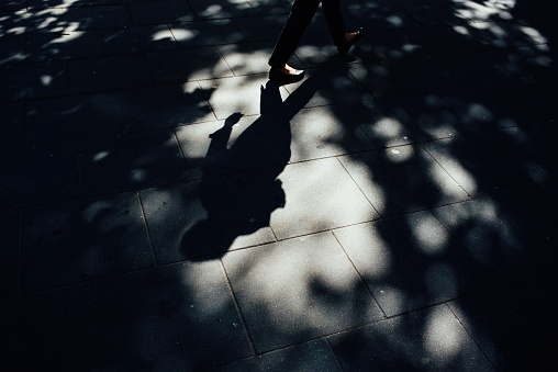 A high angle shot of the shadow of a person walking on the sidewalk