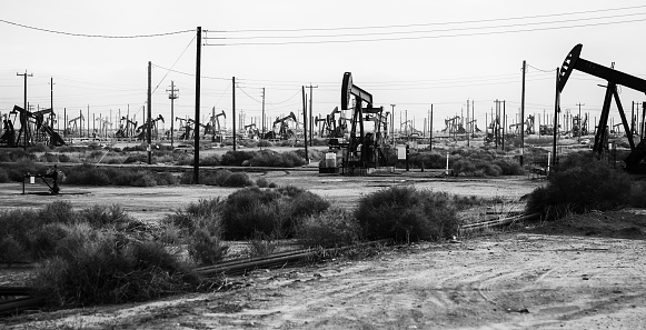 Living the Anthropocene in Lost Hills oil field rigs in black and white, stark industrial landscape of fossil fuels.