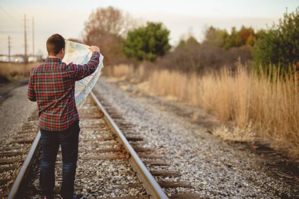 istock Shallow focus shot of a male standing on train tracks while looking at the map 1440012582