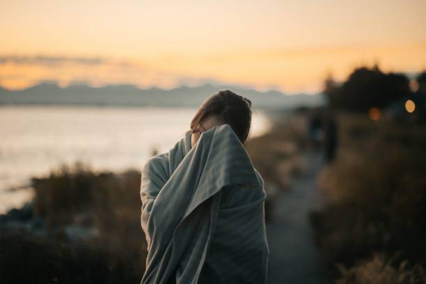 istock Selective focus on a woman, wrapped in a striped blanket, rubbing her forehead, during the sunset 1440012815