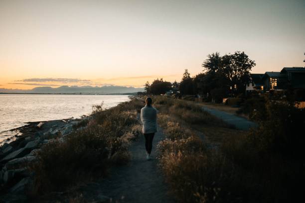 istock Woman cuddled with a blanket walking on the coastline during sunset 1440012831