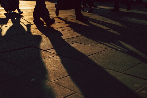 The shadow of the people stretched on the paved sidewalk