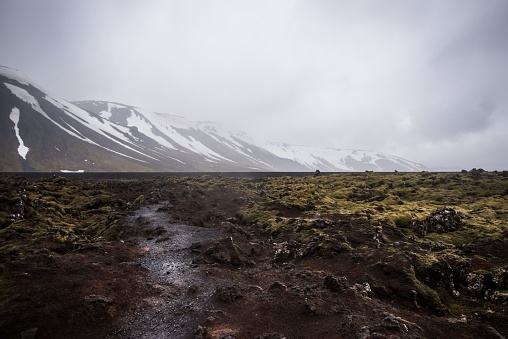 A muddy landscape in Iceland Reykjavik with mountains and cloudy sky in the background