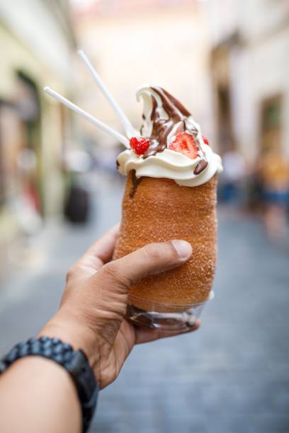 Vertical shot of a person holding a cronut ice-cream in Prague, Czech Republic A vertical shot of a person holding a cronut ice-cream in Prague, Czech Republic trdelník stock pictures, royalty-free photos & images