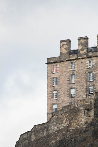 A vertical shot of a stone Building at the top of the mountain in Edinburgh