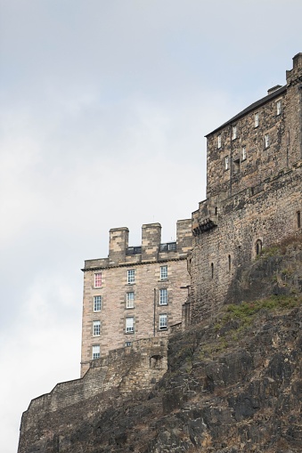 A vertical shot of a stone Building at the top of the mountain in Edinburgh