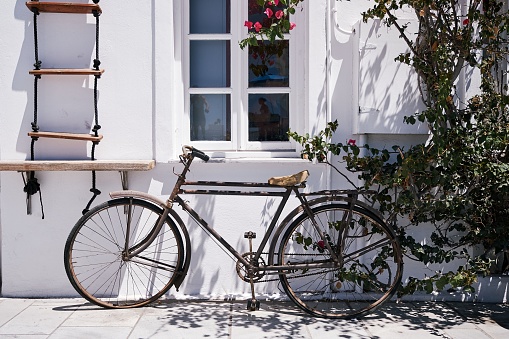 A beautiful shot of a bicycle parked under the window of a white building in Santorini, Greece