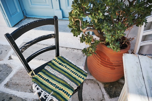A high angle shot of the outdoor of a house with a chair and a domestic plant in Naxos, Greece