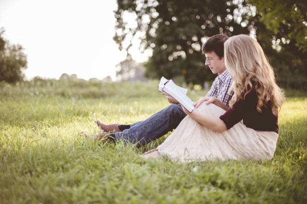 ぼやけた背景を持つ日差しの下の庭で一緒に聖書を読む夫婦 - senior couple ストックフォトと画像