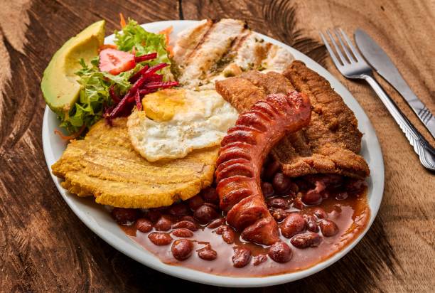 vista dall'alto di un piatto bianco con bandeja paisa con un uovo e insalata di verdure su un tavolo di legno - bandeja paisa foto e immagini stock