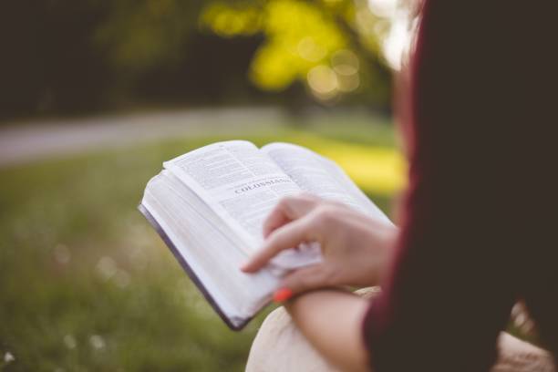 istock Closeup shot of a female sitting while reading the bible with a blurred background 1440014607