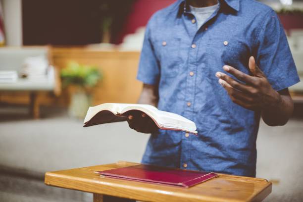 plan rapproché d’un homme lisant la bible près d’un support en bois avec un arrière-plan flou - preacher photos et images de collection