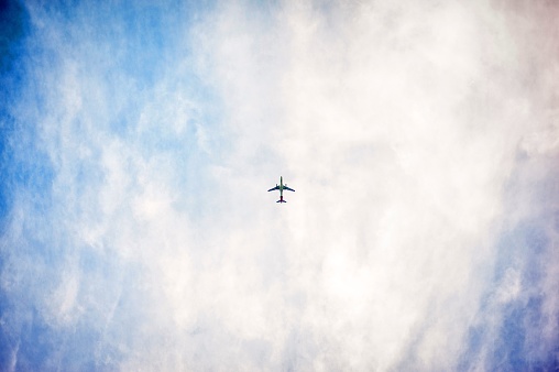 A low angle shot of an airplane flying high in the sky with pure white clouds
