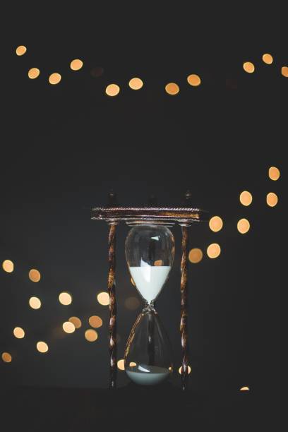 Vertical closeup shot of a sand glass timer with burred lights in the background A vertical closeup shot of a sand glass timer with burred lights in the background burred stock pictures, royalty-free photos & images