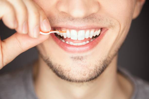 istock Male cleaning and flossing space between tooth with plastic and silicone interdental brush 1440016504