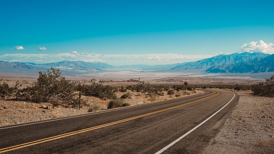 A road going through the desert with the mountains in the background captured in California