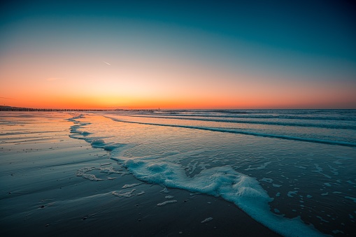 Beautiful view of the foamy waves on the beach under the sunset captured in Domburg, Netherlands