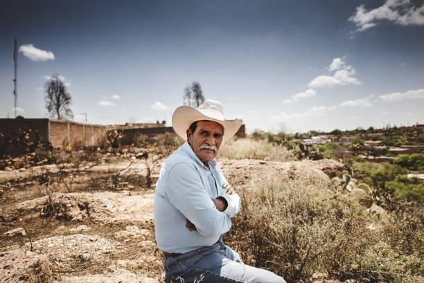 vieux cowboy mexicain assis avec une chemise en jean dans le désert - cowboy hat photos photos et images de collection