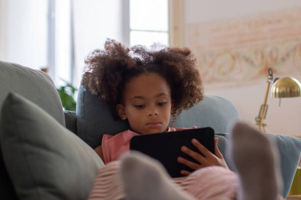 istock Absorbed little girl reading electronic book 1440017222