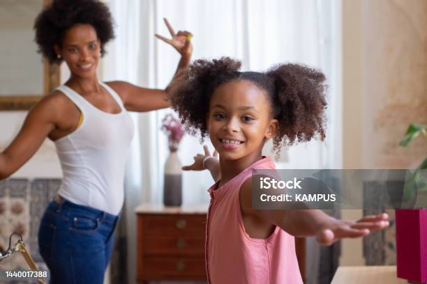 Excited African American mom and daughter dancing
