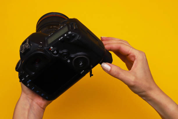 istock Digital camera in female hands removing battery for charging 1440019475