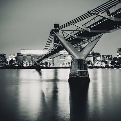A grayscale low angle shot of the London Millenium Bridge in the UK