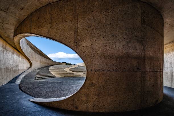 A concrete curvy arch tunnel by the highway under the cloudy sky during daytime