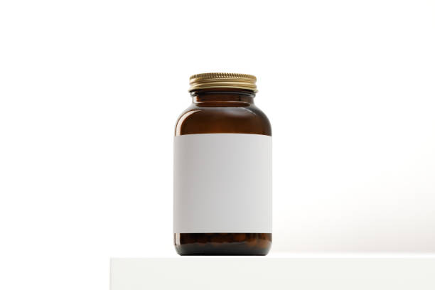 istock Glass jar with pills, medicine or vitamins on the table. Light background. 1440021490