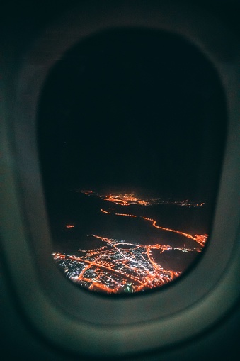 A vertical shot of a city at night taken from an airplane window