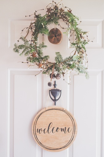 A Photo of a White Door With a Hanging Wreath and Welcome Decor