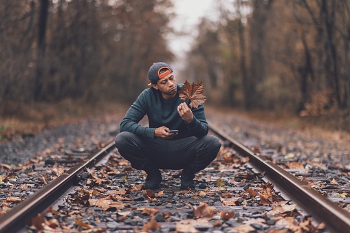 Made examines a brown leaf on abandoned train tracks