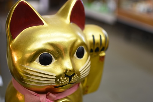 A cute selective closeup shot of a golden cat statue with a pink ribbon