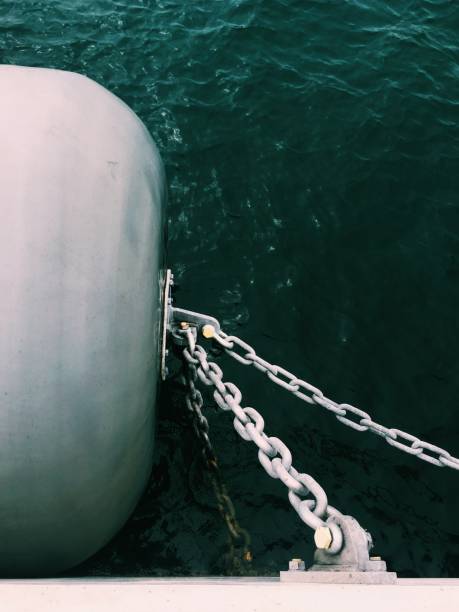 vertical shot of metal chains connected to a barrel on a side of the boat - demir zincir stok fotoğraflar ve resimler