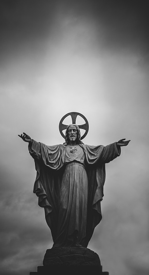 A vertical shot of a statue of the Vietnamese Jesus in black and white