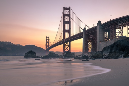 A wide shot of the Golden Gate bridge near body of water during sunset in San Francisco, California