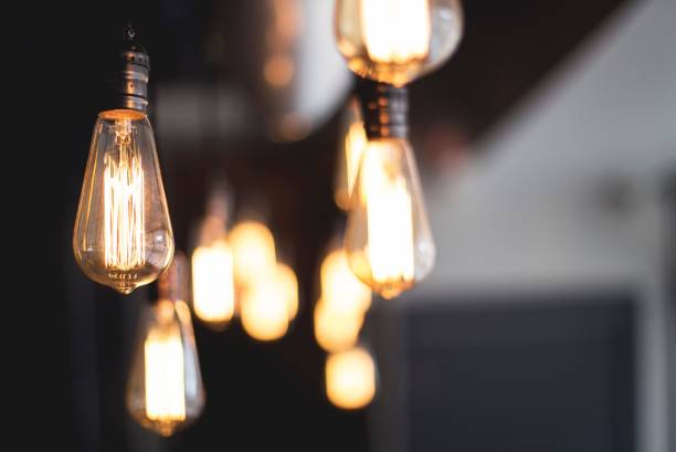 istock Wide selective closeup shot of illuminated light bulbs hanging from a ceiling 1440025868