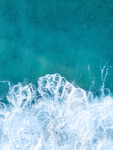 A vertical overhead shot of clear blue ocean waves