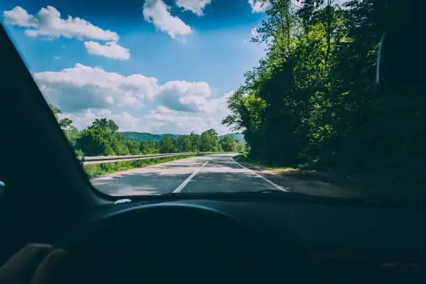 A point of view shot of a person driving a vehicle on the countryside road