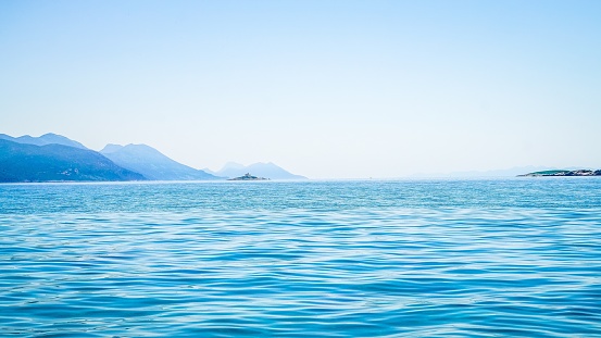 A beautiful shot of sea with a mountain in the distance and a clear sky