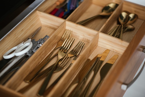 A closeup shot of a drawer with different kinds of silverware with scissors and other stuff