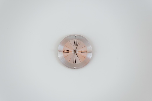 A wide shot of a rose gold wall clock on a white wall