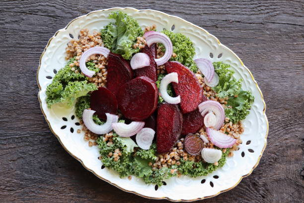 Warm buckwheat and beetroot salad on wooden background. Vegetarian diet idea and recipe -salad with beetroot, buckwheat, kale, onion, fresh herbs. Top view or flat-lay stock photo
