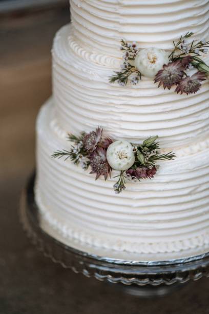 istock Vertical closeup shot of a three-layer wedding cake decorated with flowers on a silver platter 1440028424