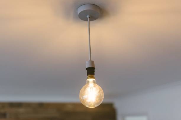 istock Closeup shot of a large illuminated light bulb hanging from the ceiling 1440028523