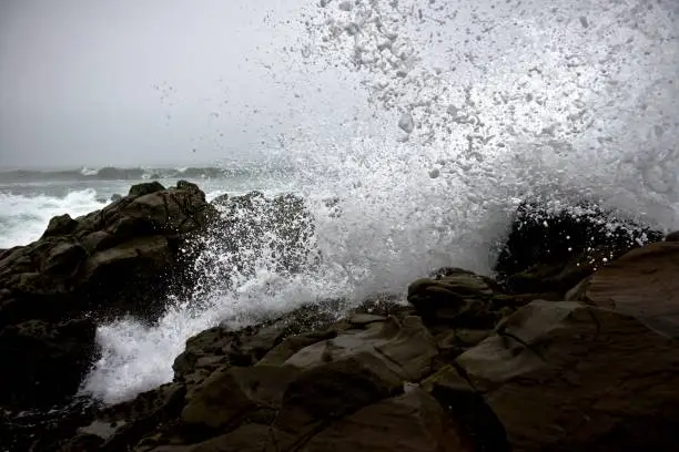 Photo of Beautiful splash of ocean waves on rocks during a rainy day