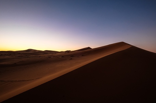A beautiful shot of sand dunes under a purple and blue sky