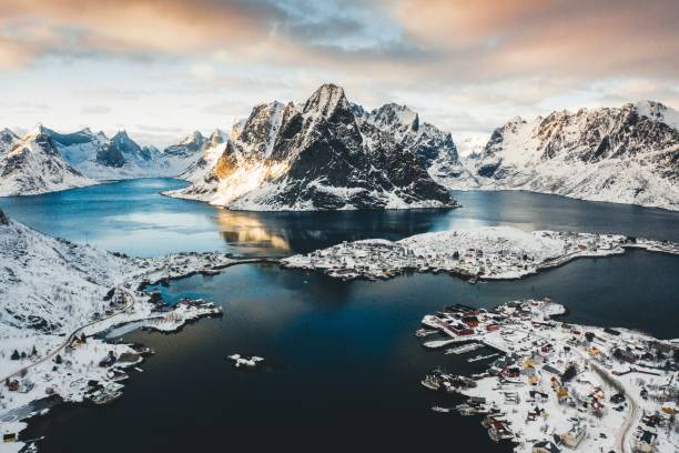Bird's-eye shot of a shore town near a body of water with snowy mountains in the background A bird's-eye shot of a shore town near a body of water with snowy mountains in the background ilulissat icefjord stock pictures, royalty-free photos & images
