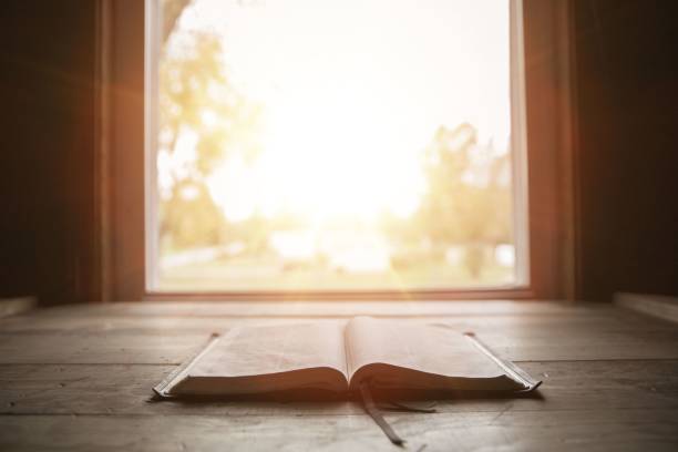 Close shot of holy bible on a wooden surface with the sun shining in the background A close shot of holy bible on a wooden surface with the sun shining in the background bible stock pictures, royalty-free photos & images