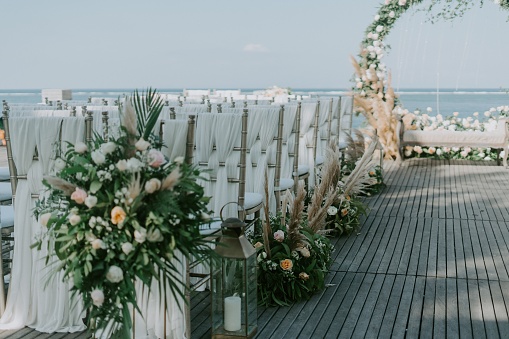 A wide shot of floral arch near the sea for a wedding ceremony during daytime